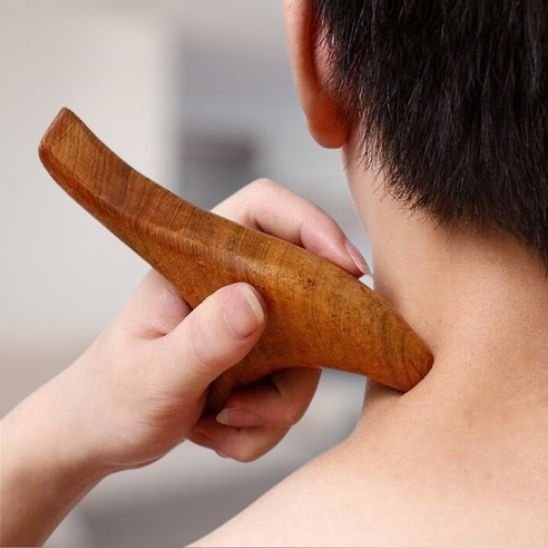 Gua sha utilisé sur l'épaule d'un homme, massage manuel