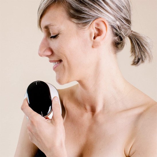 Appareil de massage appliqué sur l'épaule d'une femme aux cheveux relevés