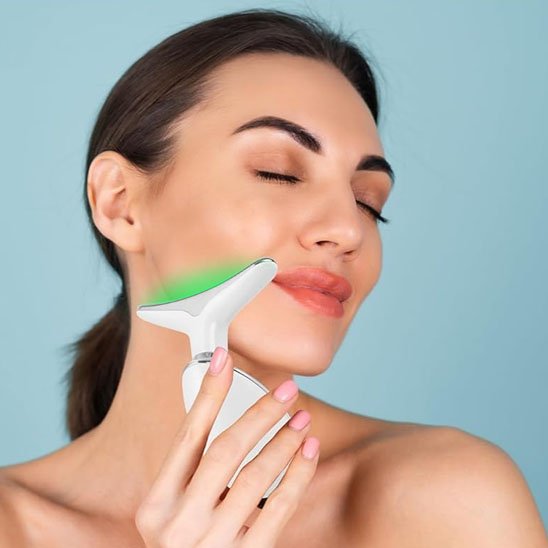 Appareil de massage glissé sur la mâchoire d'une femme souriante, soin du visage