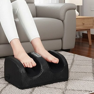Appareil masseur pieds noir sous les pieds d'une femme détendue sur son canapé