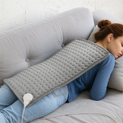 Coussin chauffant posé sur le dos d'une femme allongée sur son canapé
