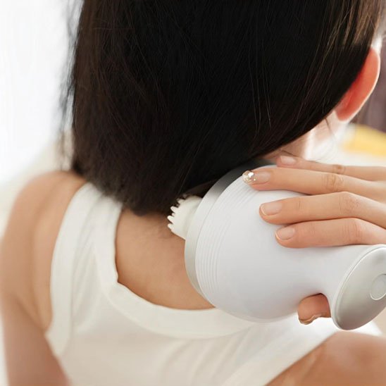 Masseur cuir chevelu utilisé sur la nuque et les épaules d'une femme détendue