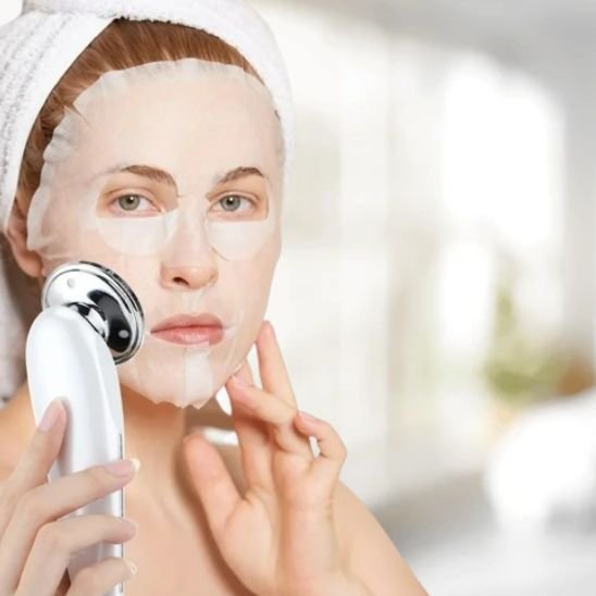 Masseur visage appliqué sur la joue d'une femme pendant sa routine beauté