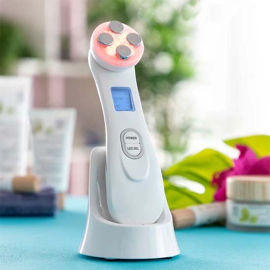 Masseur visage rose posé sur un meuble, entouré d'accessoires de soin