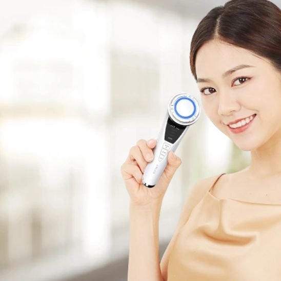 Masseur visage utilisé par une jeune femme souriante 