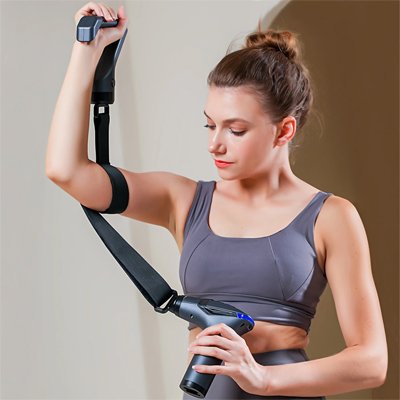 Pistolet de massage passé sur le haut de l'épaule d'une femme, bras levé après une journée de stress