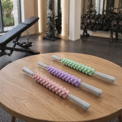 Rouleau de massage à picots multicolore posé sur une table basse en bois
